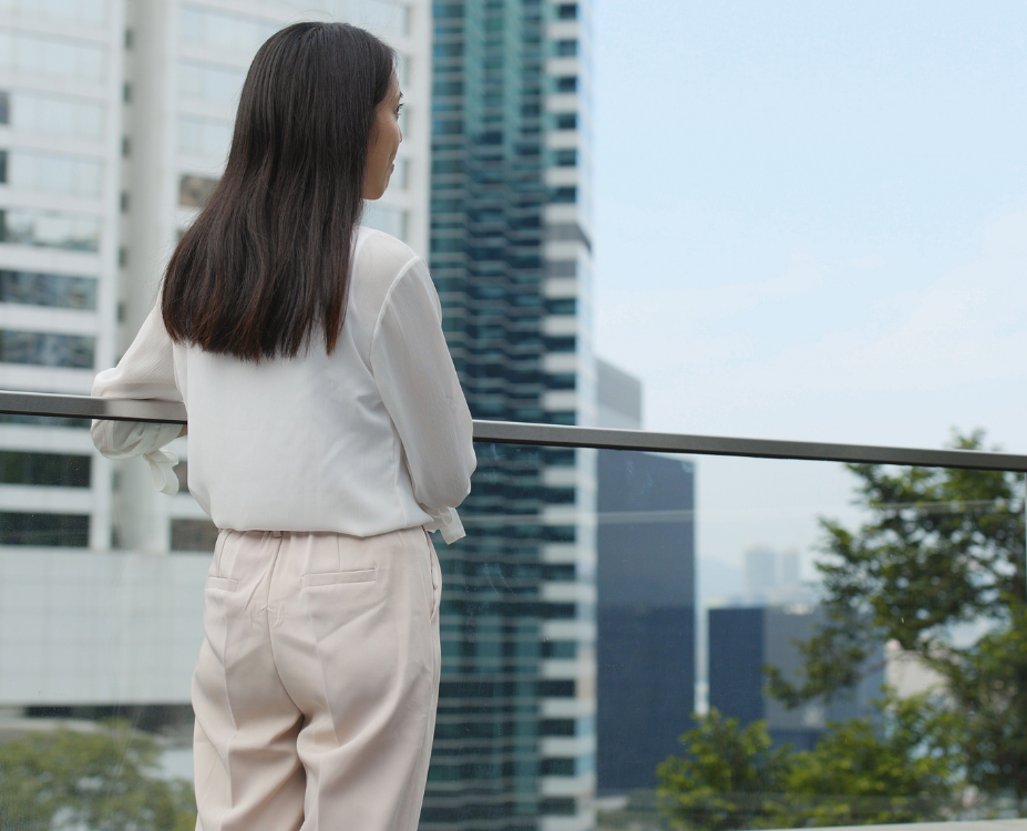 大阪の高層ビル群を眺めながら遠方の実家のお墓を思う女性